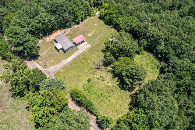 an aerial view of residential house with outdoor space and trees all around