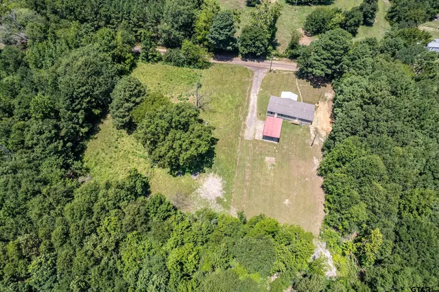 an aerial view of residential house with outdoor space and trees all around