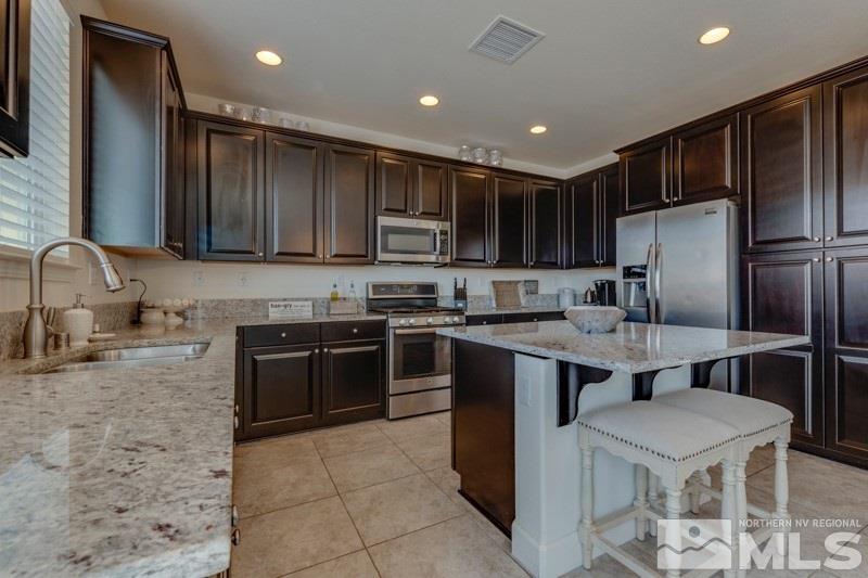10602 Washington Reno, NV 89521 - Photo 12 of 25 a kitchen with kitchen island granite countertop wooden cabinets a refrigerator and a sink