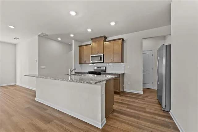 a kitchen with stainless steel appliances granite countertop a sink a stove and a wooden cabinets