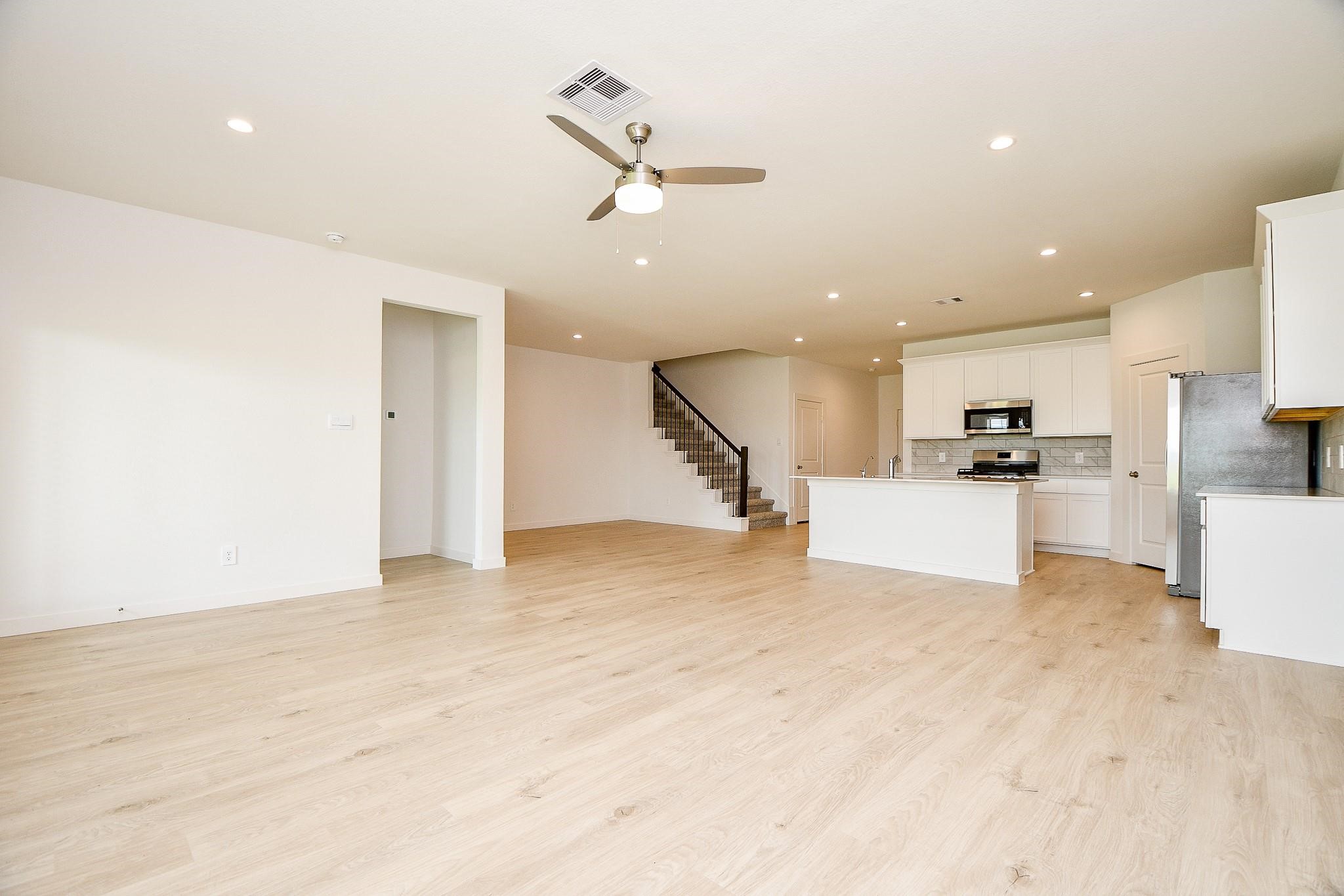 3930 Winterbourne Way Fulshear, TX 77441 - Photo 6 of 28 an empty room with kitchen view and wooden floor