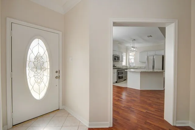 an empty room with wooden floor and a kitchen