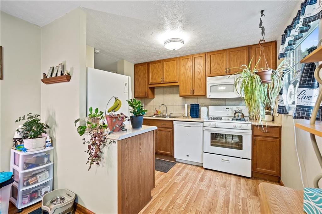 1528 O'Block Road Pittsburgh, PA 15239 - Photo 7 of 19 a kitchen with a white stove top oven and white cabinets next to a window