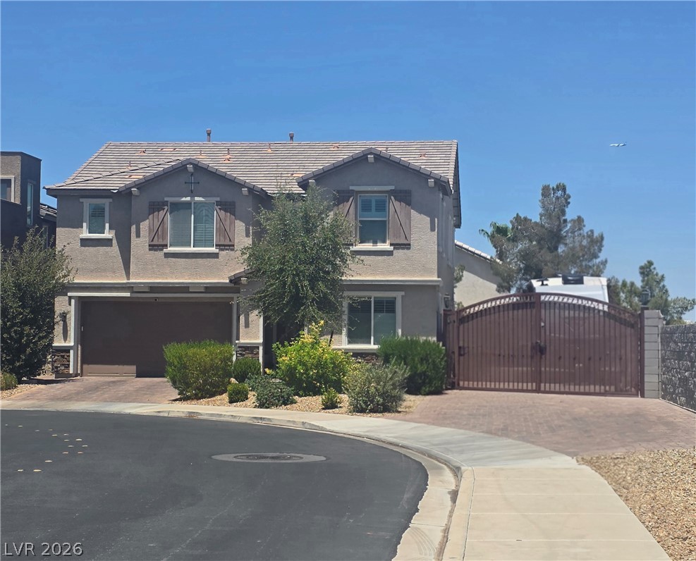 1310 Reef Point Avenue Henderson, NV 89074 - Photo 1 of 1 A classic two-story residence with a paved driveway and an elegant wrought iron gate.