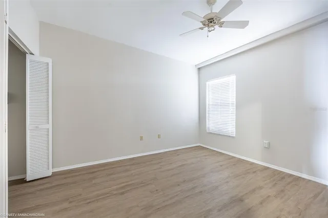 an empty room with wooden floor & closet area