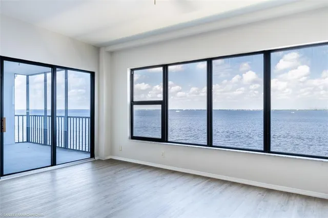a view of an empty room with wooden floor and windows