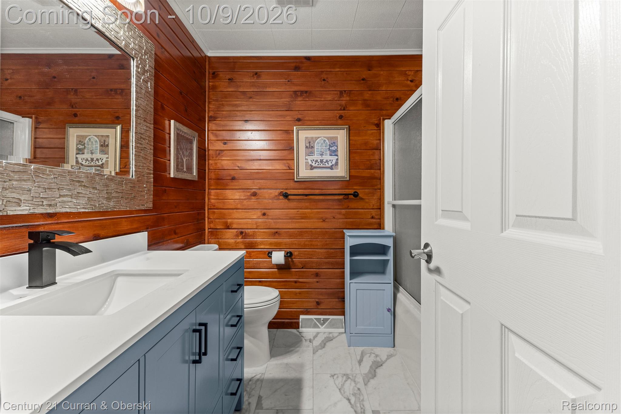 43040 Willis Road Belleville, MI 48111 - Photo 24 of 65 Wood-paneled wall, white vanity with integrated sink, matte black faucet, and stone-look tile flooring