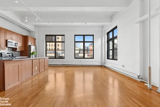 a living room with couches a coffee table and kitchen view with wooden floor