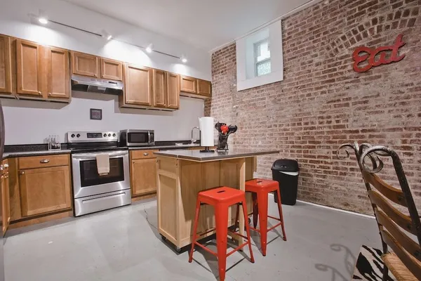 a kitchen with stainless steel appliances a stove a sink a microwave a dining table and chair