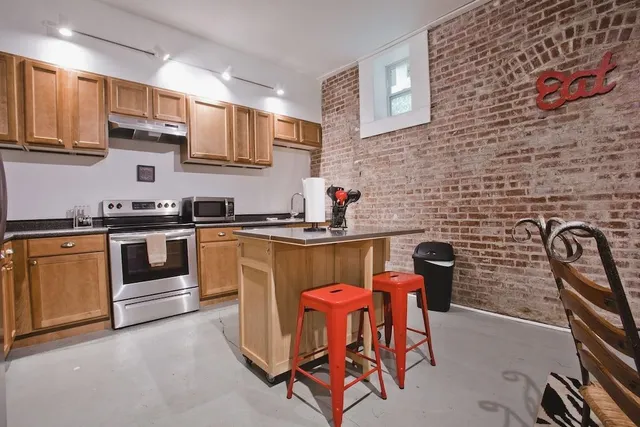 a kitchen with stainless steel appliances a stove a sink a microwave a dining table and chair