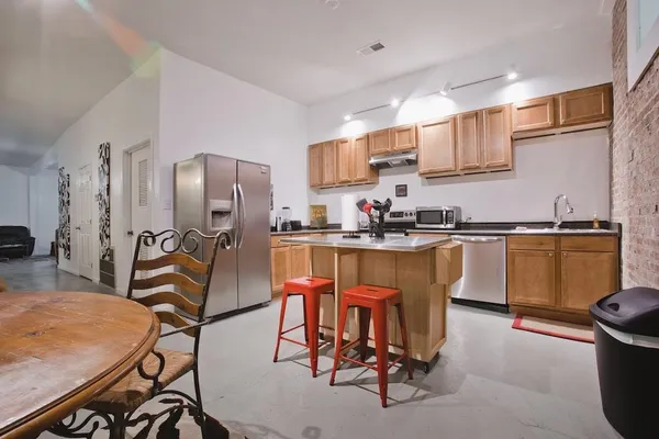 a kitchen with stainless steel appliances granite countertop a sink a stove a refrigerator cabinets and dining table