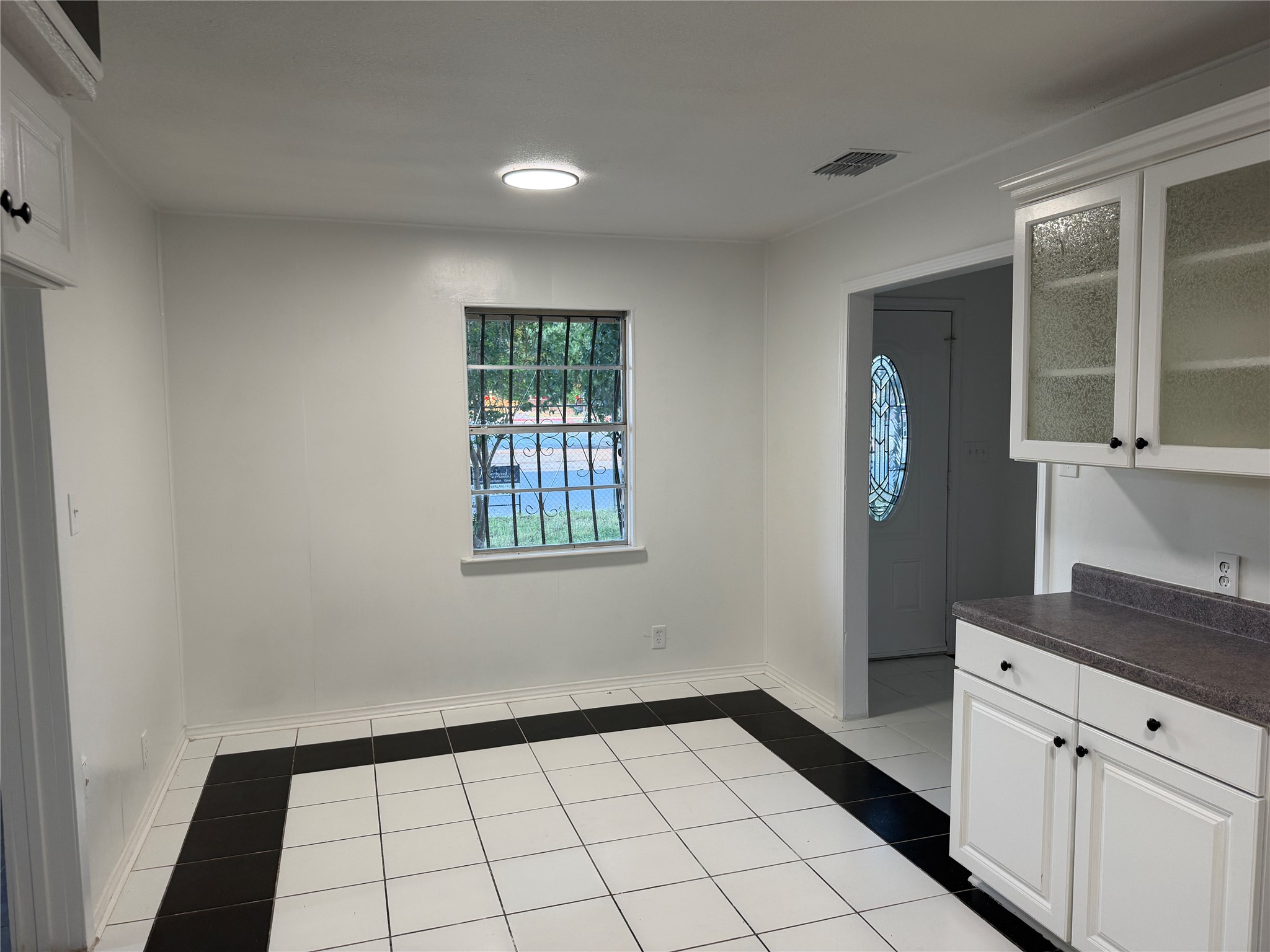 1060 Gardner Road Austin, TX 78721 - Photo 13 of 19 A compact kitchen dining area features elegant white cabinetry and patterned tile flooring.