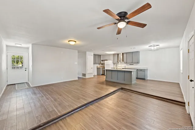 a living room with kitchen island sink and wooden floor