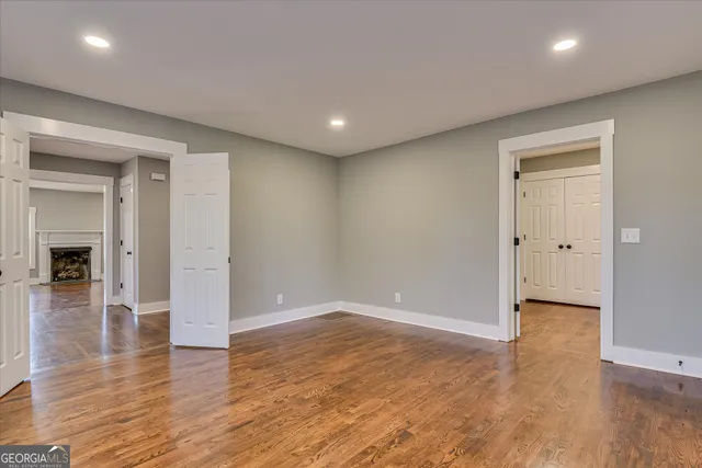 a view of an empty room with window and wooden floor