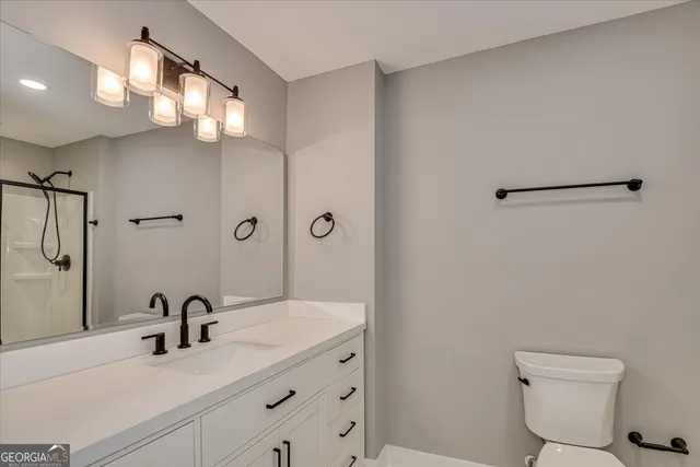 a bathroom with a sink a toilet a mirror and shower