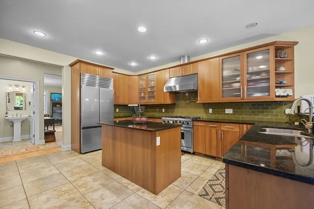 a kitchen with stainless steel appliances granite countertop a refrigerator a sink a stove top oven and a counter space
