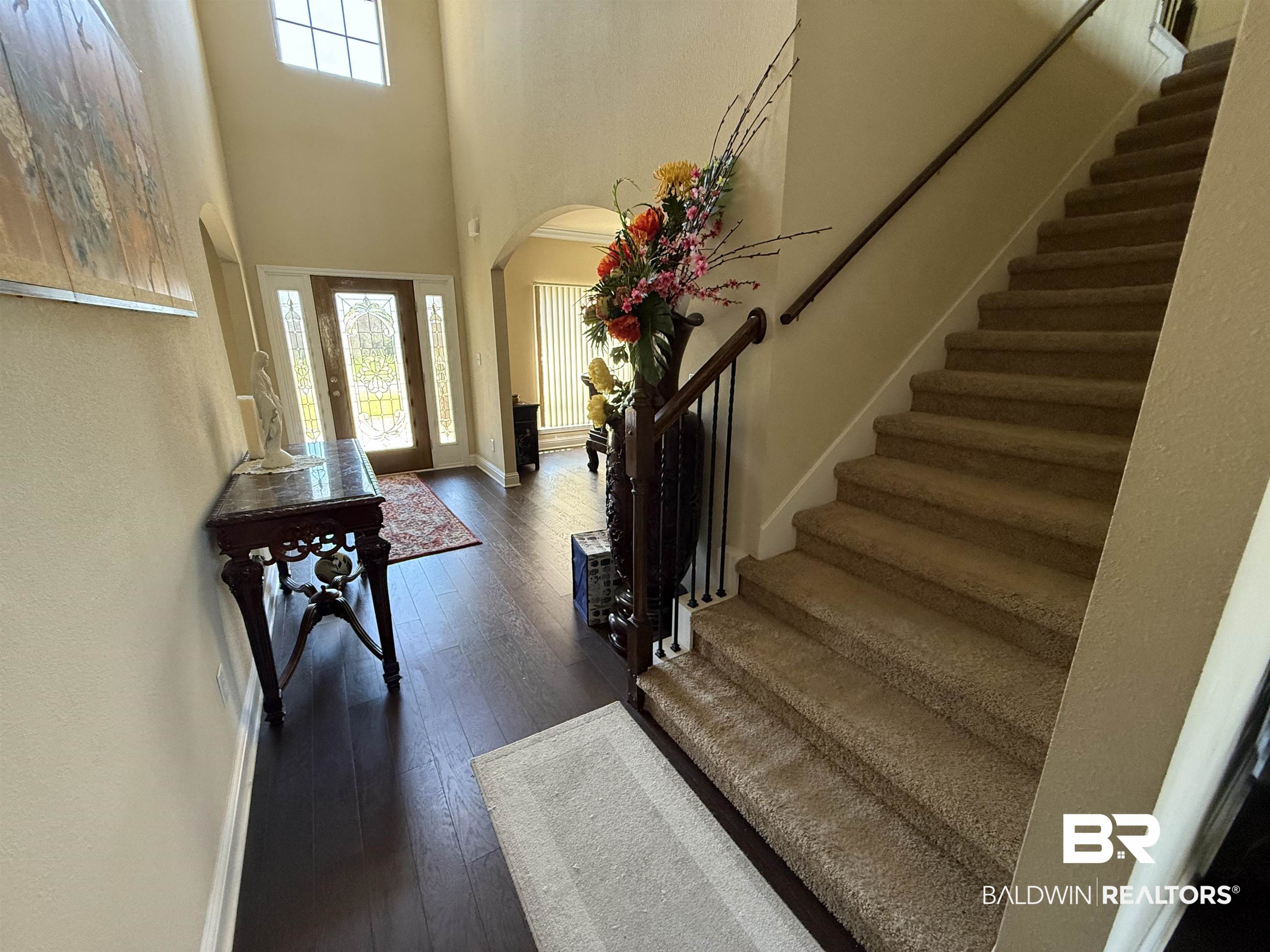 9023 Krystal Ridge Court Daphne, AL 36526 - Photo 32 of 41 Foyer featuring arched walkways, stairs, plenty of natural light, dark wood-style flooring, and a high ceiling