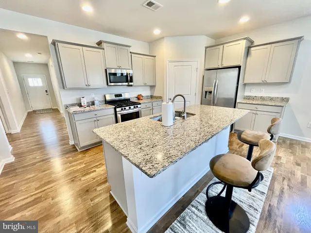 a kitchen with stainless steel appliances granite countertop a table chairs sink and microwave