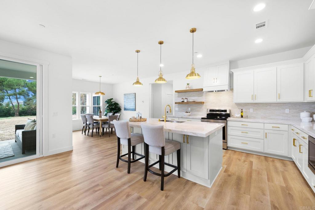 1547 Dickey Street Fallbrook, CA 92028 - Photo 10 of 45 a kitchen with stainless steel appliances a dining table chairs stove and white cabinets