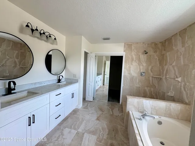 a bathroom with a double vanity sink mirror and bathtub