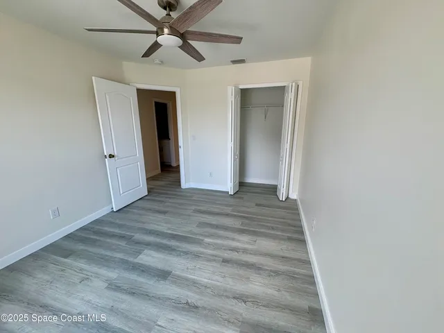 a view of a hallway with closet and a ceiling fan