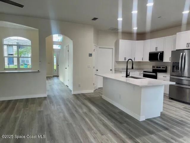 a kitchen with stainless steel appliances a sink cabinets and wooden floor