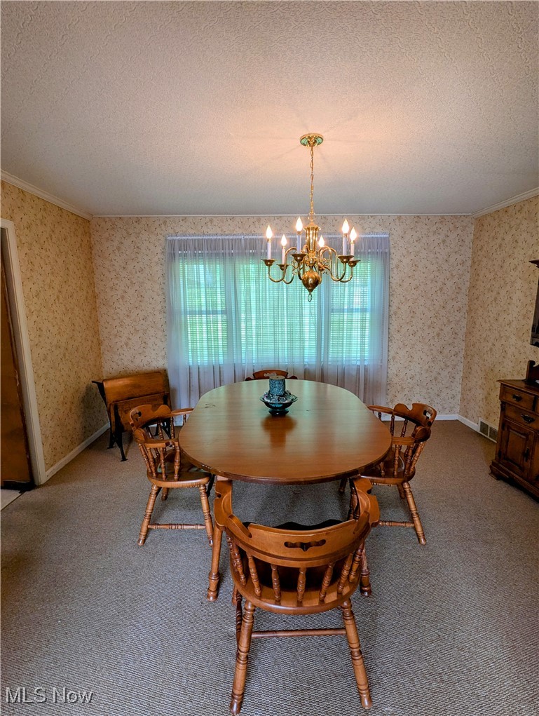 4965 Atchison Road Bellaire, OH 43906 - Photo 11 of 23 Dining space with a chandelier, a textured ceiling, wallpapered walls, ornamental molding, and carpet flooring