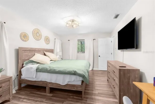 a spacious bedroom with a bed and a flat screen tv