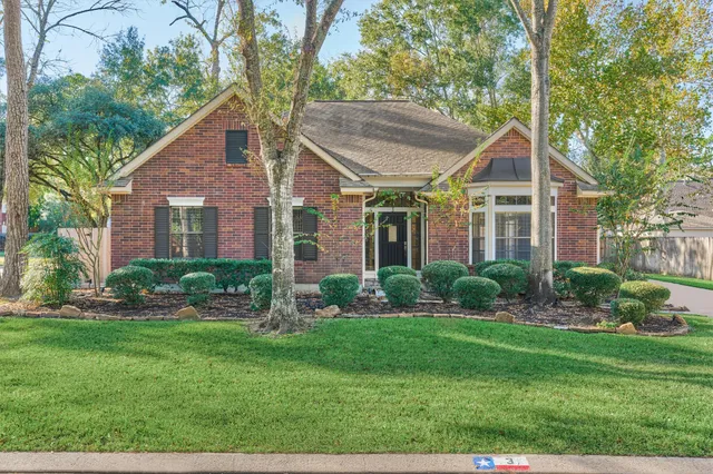 a view of a house next to a big yard and large trees