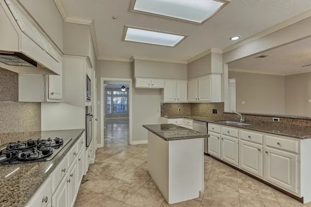 a kitchen with granite countertop a sink and a stove top oven