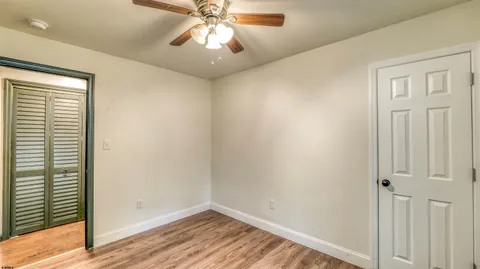 an empty room with wooden floor closet and windows
