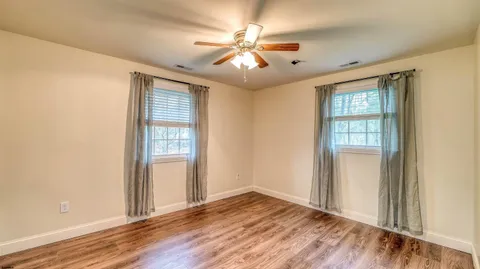 a view of an empty room with wooden floor and a window