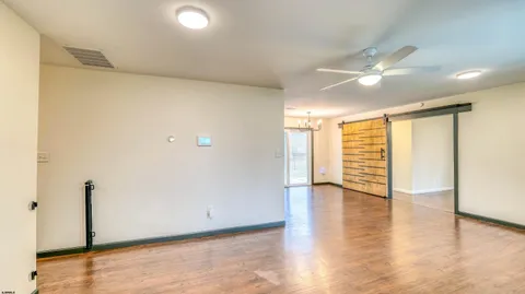 an empty room with wooden floor and windows with curtains