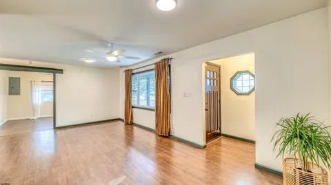 a view of an empty room with wooden floor and a window