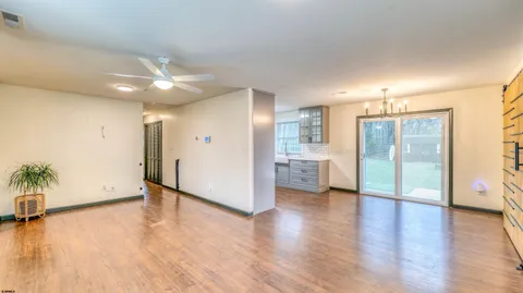 an empty room with wooden floor and a kitchen