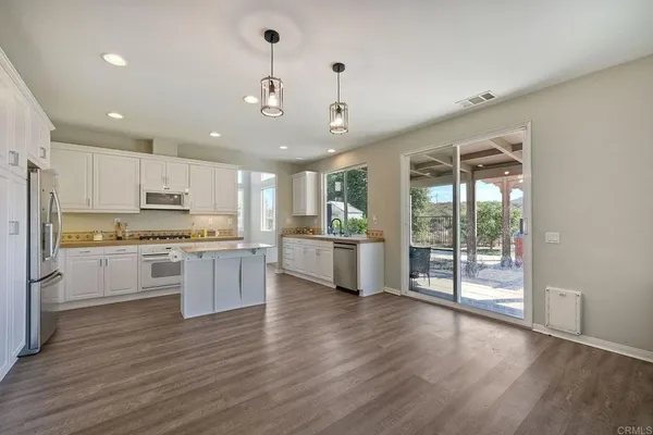 a large kitchen with white cabinets and wooden floor