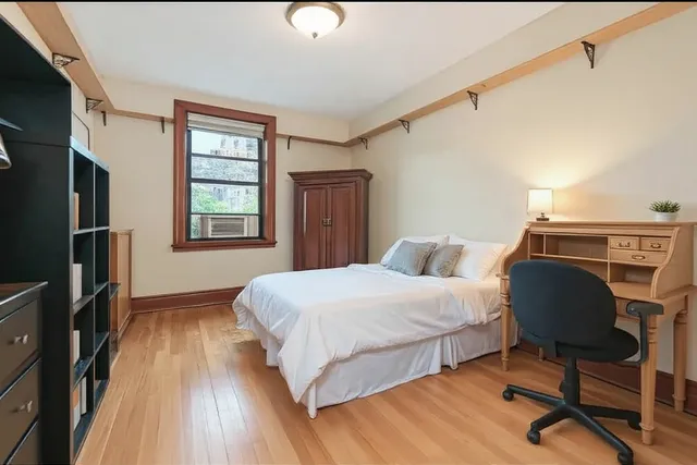 a bedroom with a bed a bookshelf a desk and chair with wooden floor