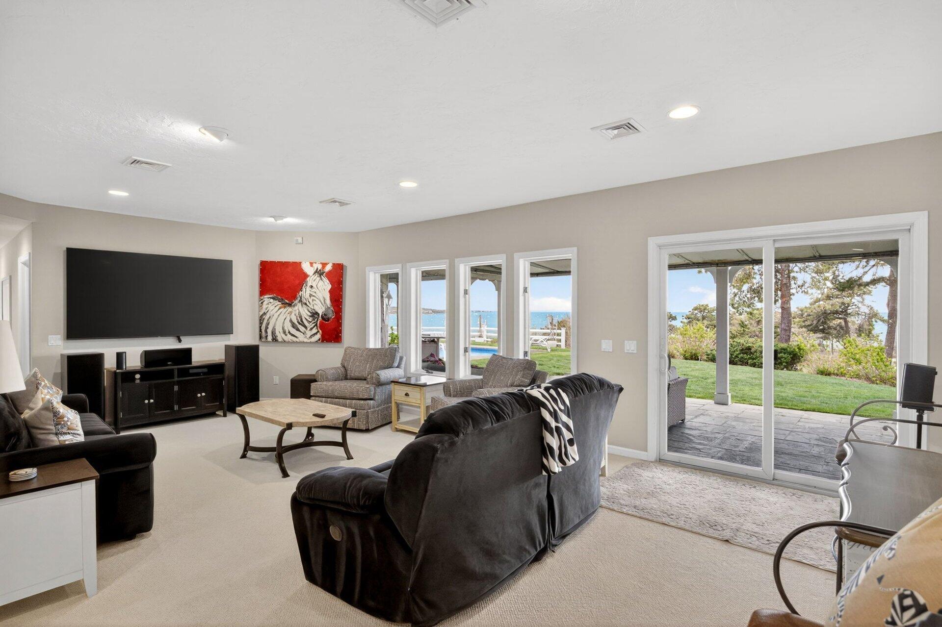 461 Wings Neck Road Pocasset, MA 02559 - Photo 32 of 42 a living room with furniture a flat screen tv and a floor to ceiling window