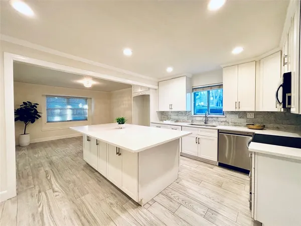 a large white kitchen with wooden floors and white cabinets