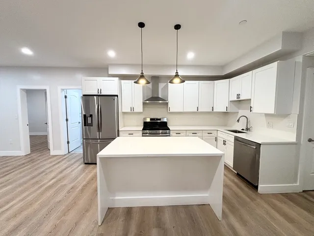 a kitchen with stainless steel appliances kitchen island a refrigerator sink and cabinets