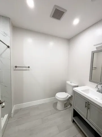 a bathroom with a toilet a sink and mirror