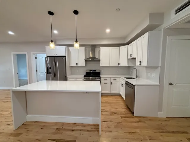 a kitchen with kitchen island a sink a stove a refrigerator and white cabinets