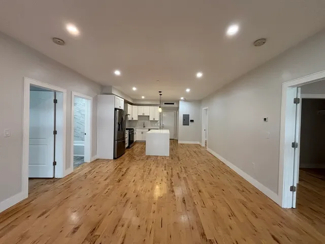 a view of a livingroom with a kitchen space and wooden floor