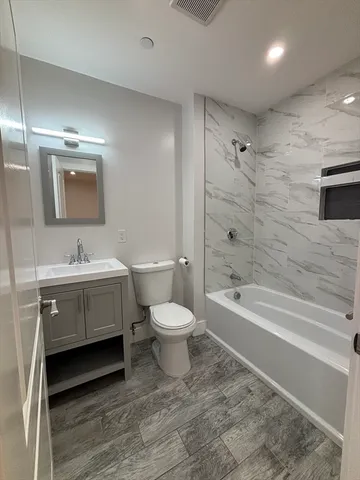 a bathroom with a toilet a sink a mirror and a bathtub