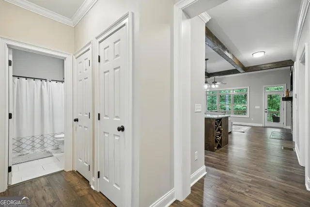 a view of a hallway with wooden floor and a bathroom