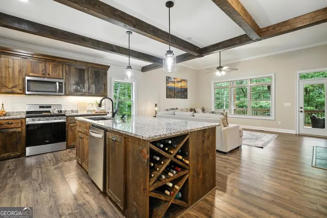 a kitchen with granite countertop a stove top oven a sink dishwasher white cabinets and wooden floor
