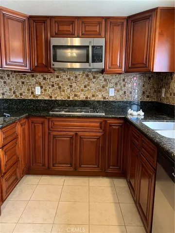 a kitchen with stainless steel appliances granite countertop wooden cabinets a stove top oven a sink and dishwasher