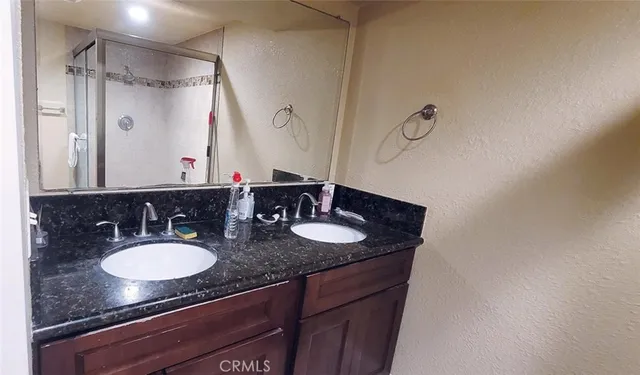 a bathroom with a granite countertop sink a mirror and a shower