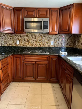 a kitchen with stainless steel appliances granite countertop wooden cabinets a stove top oven a sink and dishwasher