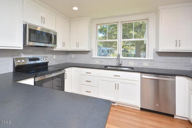 a kitchen with granite countertop a stove a sink and a microwave